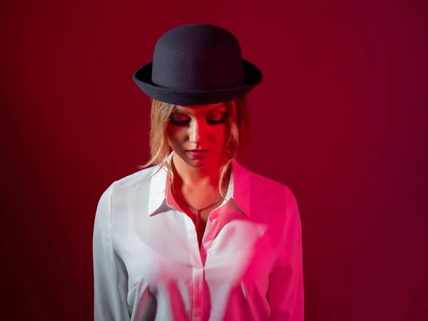 Una joven mujer con estilo en una camisa blanca y un sombrero de boliche negro, estilo estricto, —  Fotos de Stock