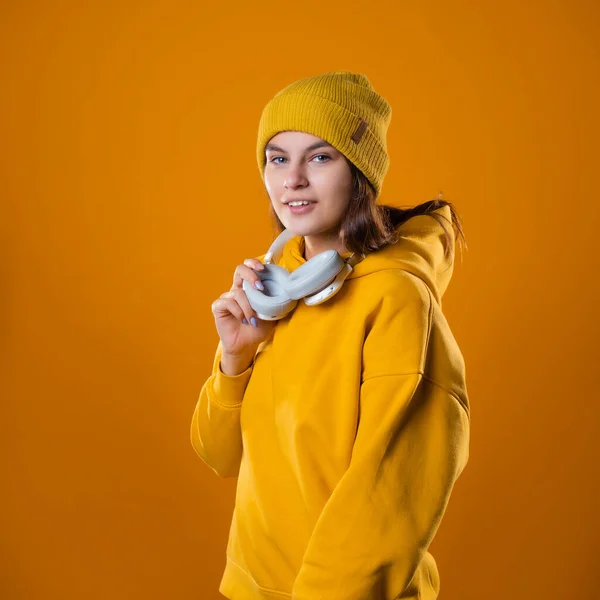 A music lover, a young cheerful brunette in bright clothes listens to music — Stock Photo, Image