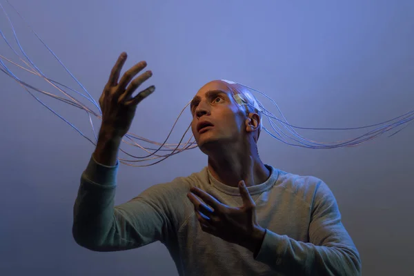 Un joven con la cabeza enredada con cables, levanta las manos, — Foto de Stock