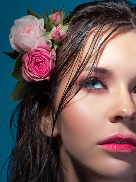 Uma jovem mulher bonita com flores de rosa em seu cabelo molhado. — Fotografia de Stock