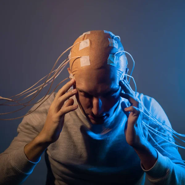Um jovem assustador com a cabeça emaranhada de fios, toca a cabeça — Fotografia de Stock