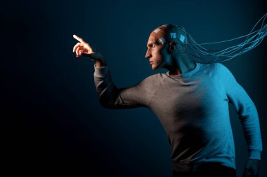 Kafası kabloya dolanmış genç bir adam ellerini öne çekiyor.,