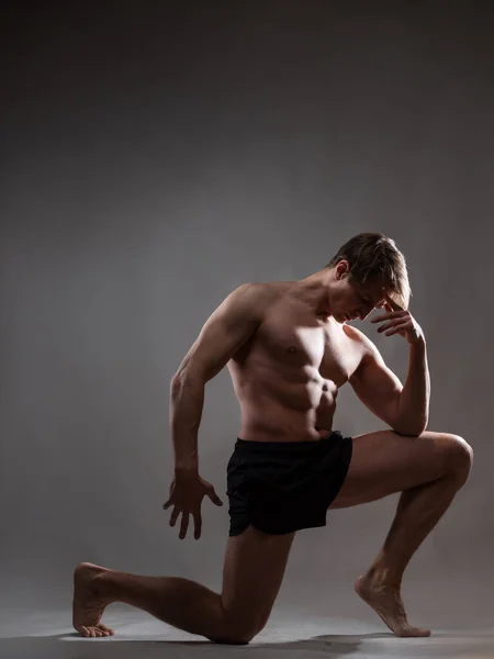 Ein junger muskulöser Mann in ausdrucksstarker Pose. Schöne Muskeln. — Stockfoto