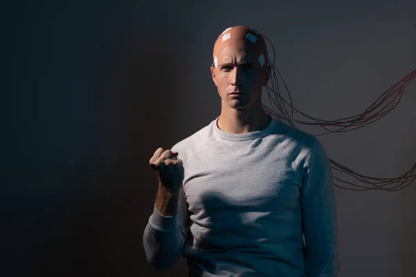 A young man with his head entangled with wires, electrical contacts on his head, — Stock Photo, Image