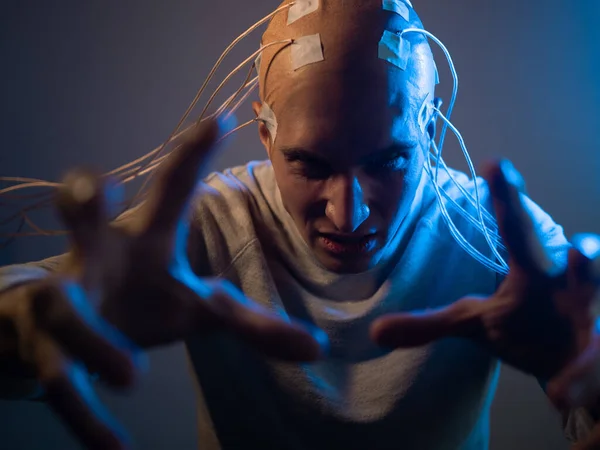 Un joven aterrador con la cabeza enredada en cables, usa el control mental —  Fotos de Stock