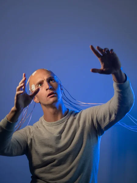 Un joven con la cabeza enredada con cables, levanta las manos, — Foto de Stock