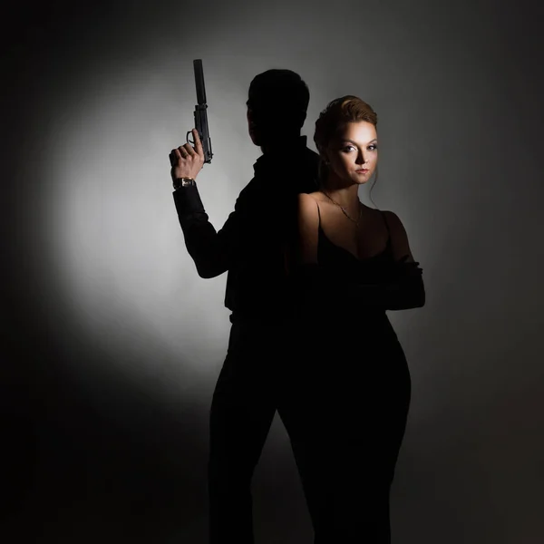 Superagenten, eine hinreißende Blondine im schwarzen Abendoutfit und ein Mann mit Waffe — Stockfoto