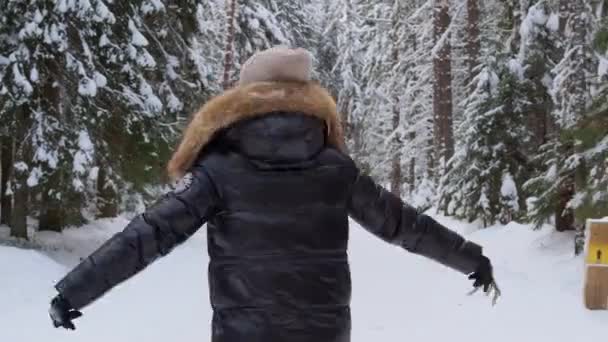 A young woman in a fluffy hood walks in the winter forest. enjoy nature. — 图库视频影像