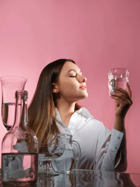 Uma bela jovem morena segura um copo de água limpa em suas mãos, — Fotografia de Stock