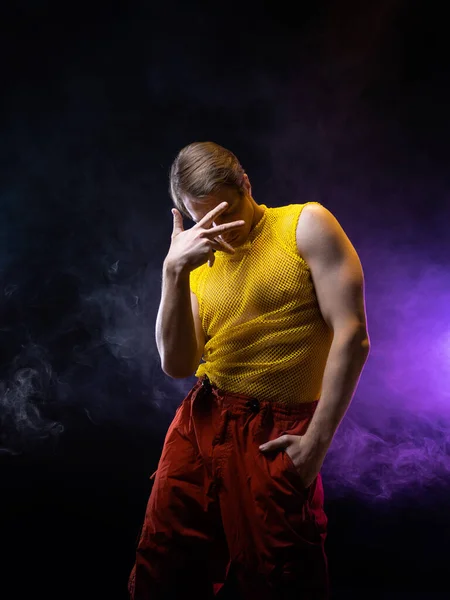 En ung muskulös man i en ljus outfit utgör i en pretentiös pose, stil — Stockfoto