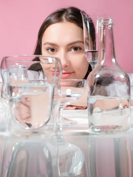 Retrato de uma jovem morena em refração através de copos de água — Fotografia de Stock
