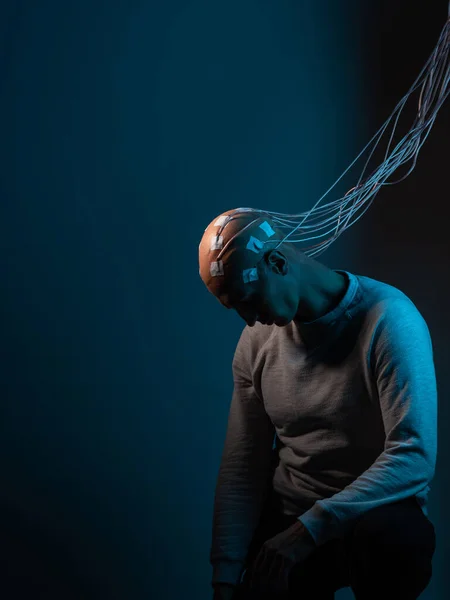 Young man with his head entangled in wires, turned off, sits with his head down, — Stock Photo, Image