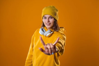 Sarı kapüşonlu ve şapkalı şık, neşeli, genç bir esmer.,