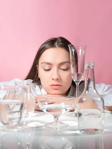 Krásná mladá brunetka mezi sklenicemi čisté vody, výhody čisté vody — Stock fotografie