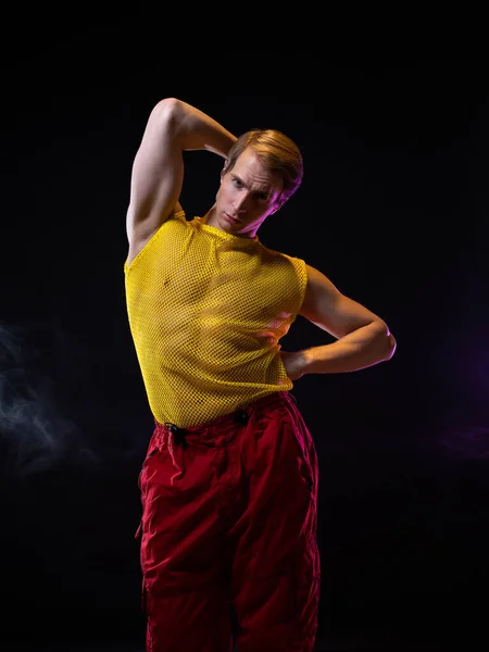 Um jovem homem musculoso em uma roupa brilhante posa em uma pose pretensiosa, — Fotografia de Stock