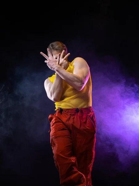 En ung muskulös man i en ljus outfit utgör i en pretentiös pose, stil — Stockfoto