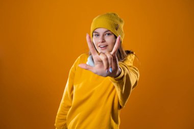 Sarı kapüşonlu ve şapkalı şık, neşeli, genç bir esmer.,