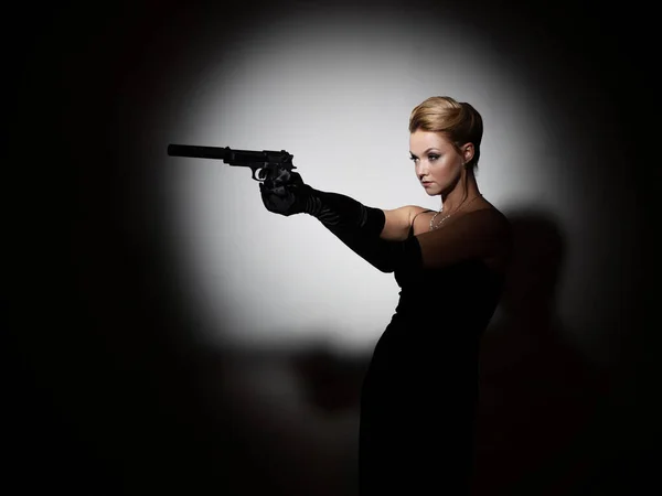 Μια μοιραία γυναίκα σημαδεύει ένα σιγανό πιστόλι, έναν κατάσκοπο ή έναν μυστικό πράκτορα.. — Φωτογραφία Αρχείου