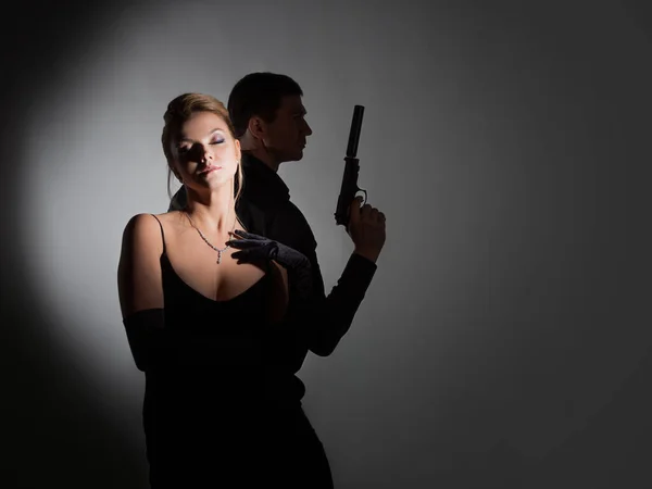 Superagenten, eine hinreißende Blondine im schwarzen Abendoutfit und ein Mann mit Waffe — Stockfoto