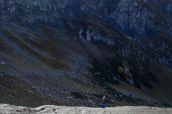 Egy ember a hegyi úton, egy hatalmas szikla és egy apró emberi alak., — Stock Fotó