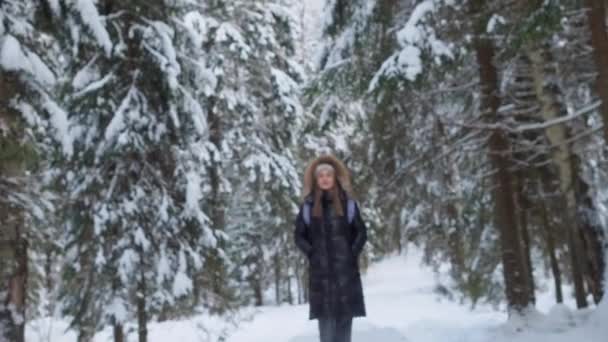 A young woman in a fluffy hood walks in the winter forest. enjoy nature. — Video Stock