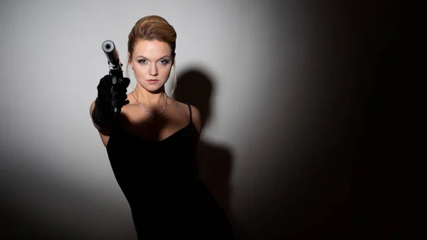 Роковая женщина нацелена на пистолет с глушителем, шпиона или агента под прикрытием. — стоковое фото