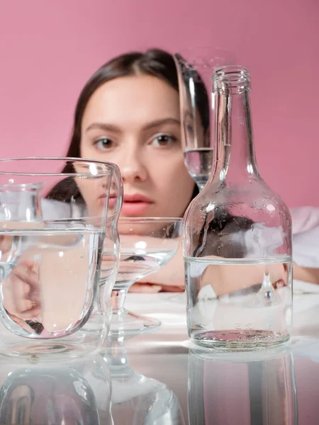 Retrato de una joven morena en refracción a través de vasos de agua — Foto de Stock