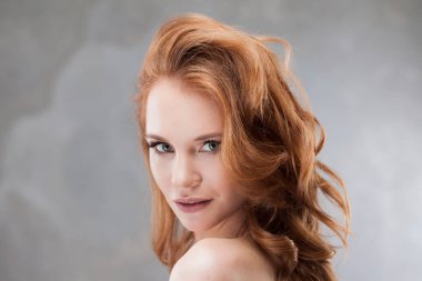 Genç, çekici, kızıl saçlı, açık tenli, narin portresi olan bir kadın.