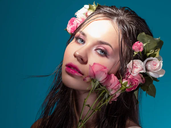 Uma jovem mulher bonita com flores de rosa em seu cabelo molhado. — Fotografia de Stock