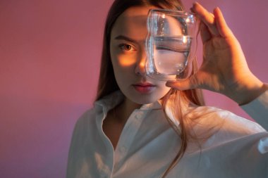 Güzel, genç bir esmer elinde bir bardak temiz su tutuyor.,