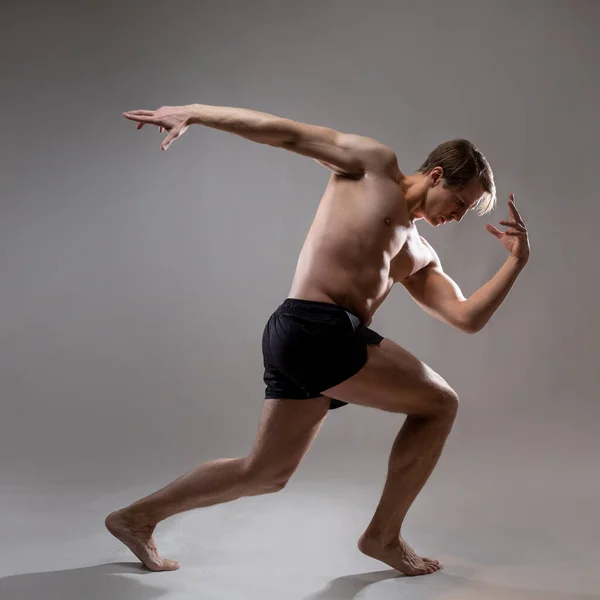 Um jovem homem musculoso em uma pose expressiva. Belos músculos. — Fotografia de Stock