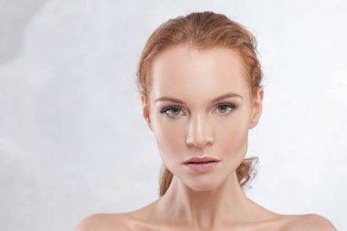 Genç, çekici, kızıl saçlı, açık tenli, narin portresi olan bir kadın.