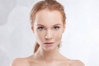 Genç, çekici, kızıl saçlı, açık tenli, narin portresi olan bir kadın.