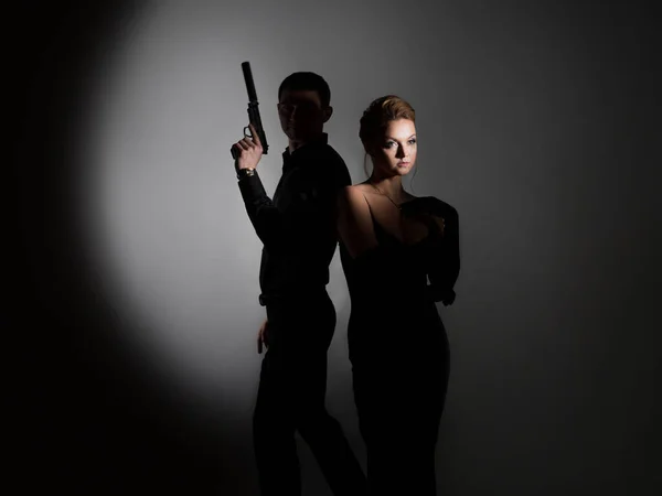 Super agents, a gorgeous blonde in a black evening outfit and a man with a gun — Stockfoto