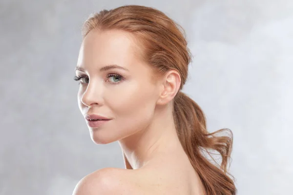 En ung attraktiv rödhårig kvinna med klar hud, porträtt i profil Stockfoto