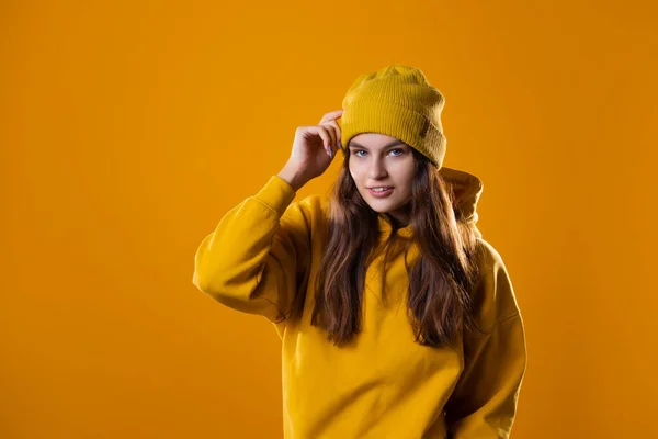 Стильна весела молода брюнетка в жовтому светрі і капелюсі на жовтому — стокове фото