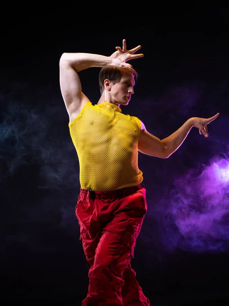 En ung muskulös man i en ljus outfit utgör i en pretentiös pose, — Stockfoto