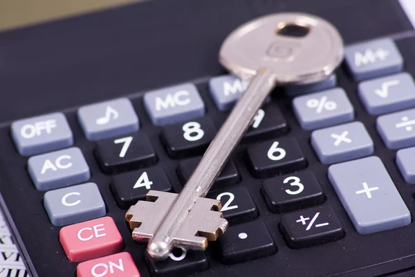 Black calculator with a key isolated on a white background — Stock Photo, Image