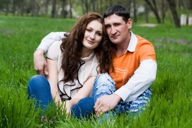 açık havada gülümseyerek oturan Çift