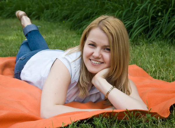 魅力的な若い女性は緑の草に横になっています。 — ストック写真