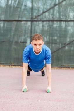 Fitness adamı dambıl sırası egzersizi yapıyor dambıl kaldırıyor, halter ağırlıklarını kaldırıyor, arka sıra egzersizleri yapıyor ya da komando sırasını değiştiriyor. 