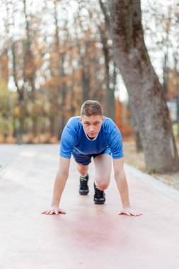 Başlangıç pozisyonunda genç bir sporcu yarış başlatmaya hazır. Erkek koşucu koşuya hazır. 