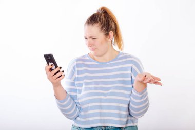 Kız öfkeyle beyaz bir stüdyonun arka planındaki telefondan bilgi alıyor.