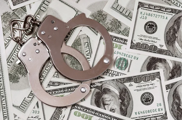 Доллары и наручники — стоковое фото