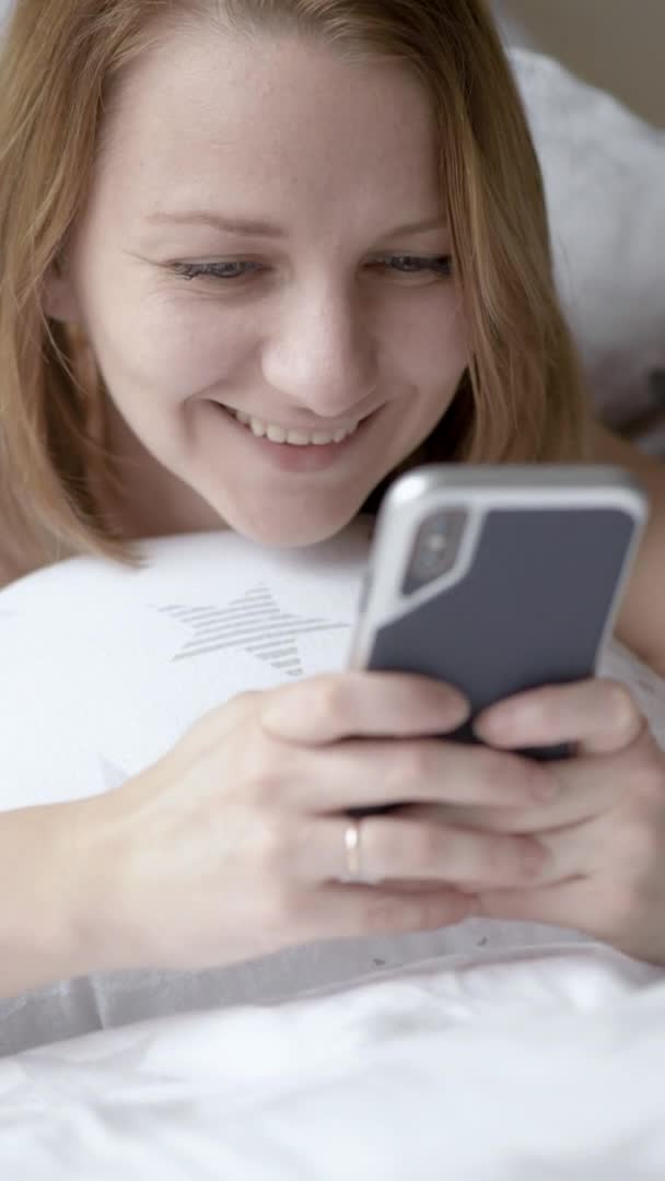 Жінка використовує мобільний телефон на ліжку — стокове відео