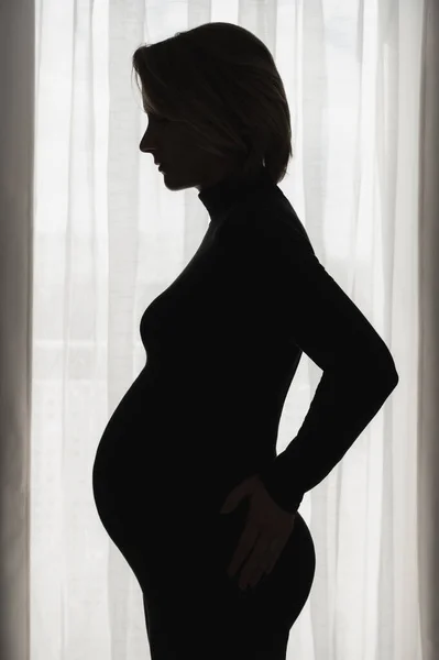 Pregnant woman against window — Stock Fotó