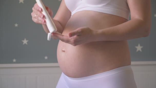 Беременная женщина со сливками для живота — стоковое видео