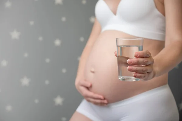 Donna incinta con bicchiere d'acqua — Foto Stock