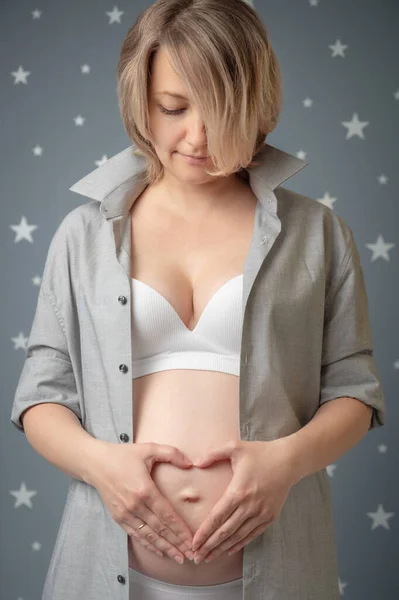 Kobieta w ciąży w koszuli pokazuje serca — Zdjęcie stockowe