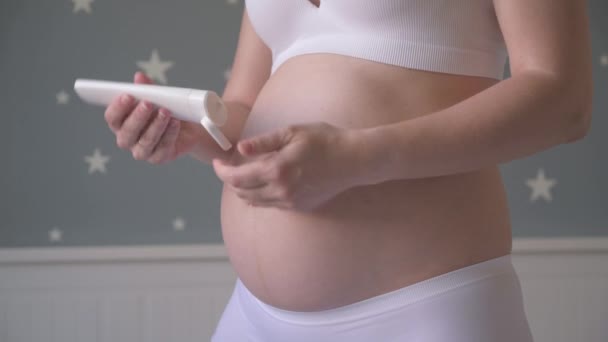 Zwangere vrouw met crème voor buik — Stockvideo